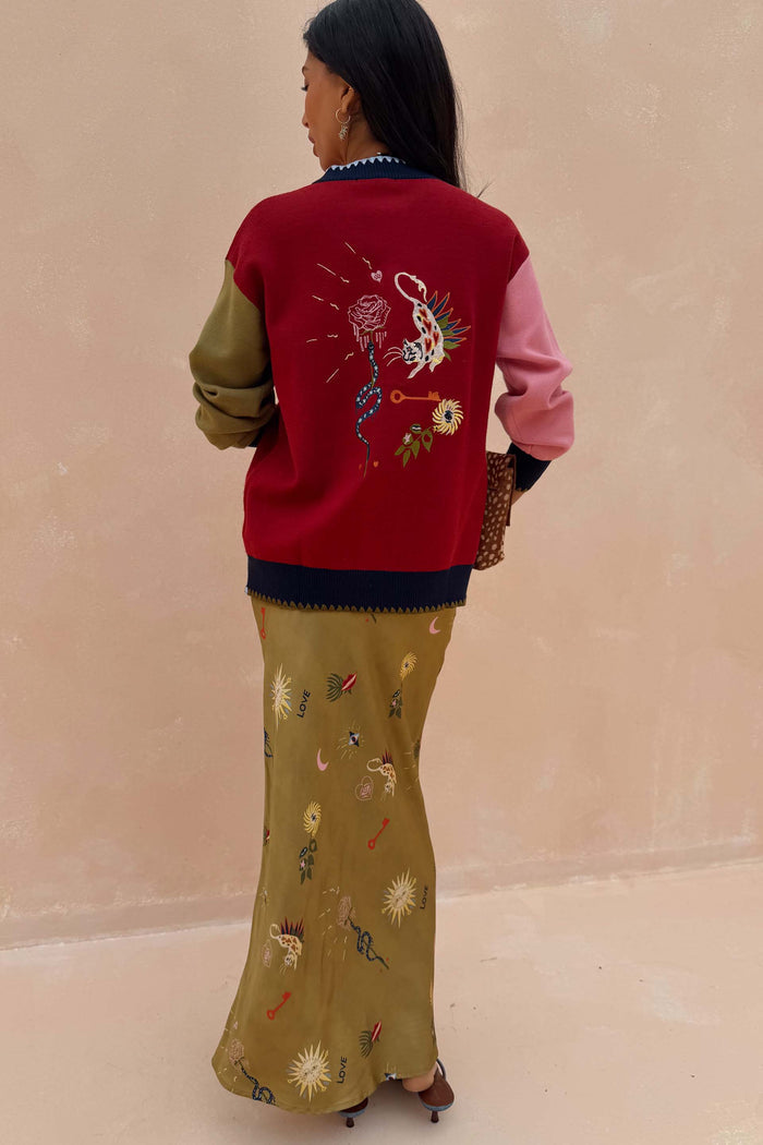 Mystical Martha Cardigan with embroidered motifs on a red back and contrast sleeves, styled with a matching patterned skirt.