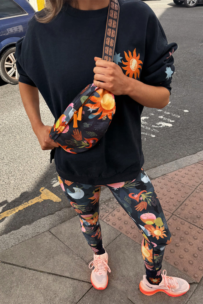Navy Charm Bumbag featuring colourful hand-painted icons, worn across the chest for a vibrant street style look.