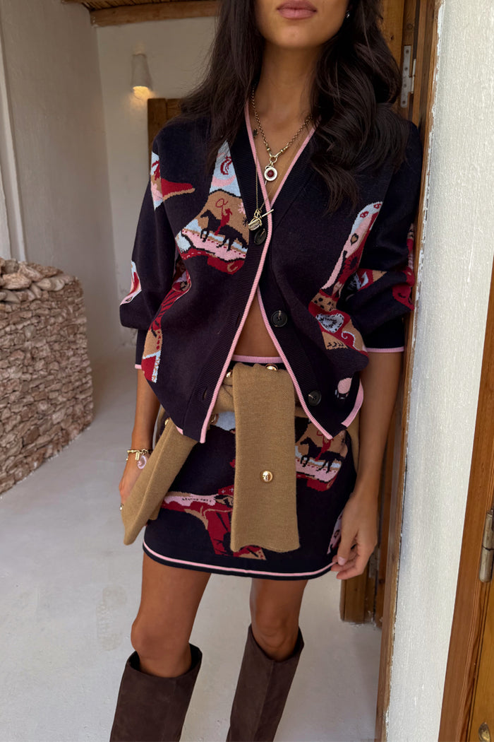 Navy Cowboy Boots Cardigan with pink contrast trims and motifs, styled with a matching skirt and boots.