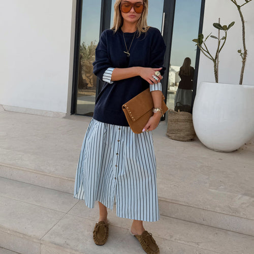 Navy Knit Jumper Dress with a blue stripe cotton skirt, styled with a tan suede clutch for a casual London look.