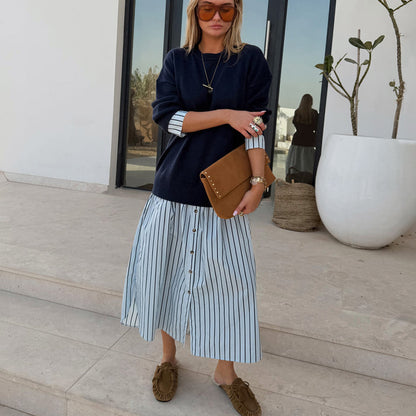 Navy Knit Jumper Dress with a blue striped cotton skirt and button front, styled with a brown suede clutch.