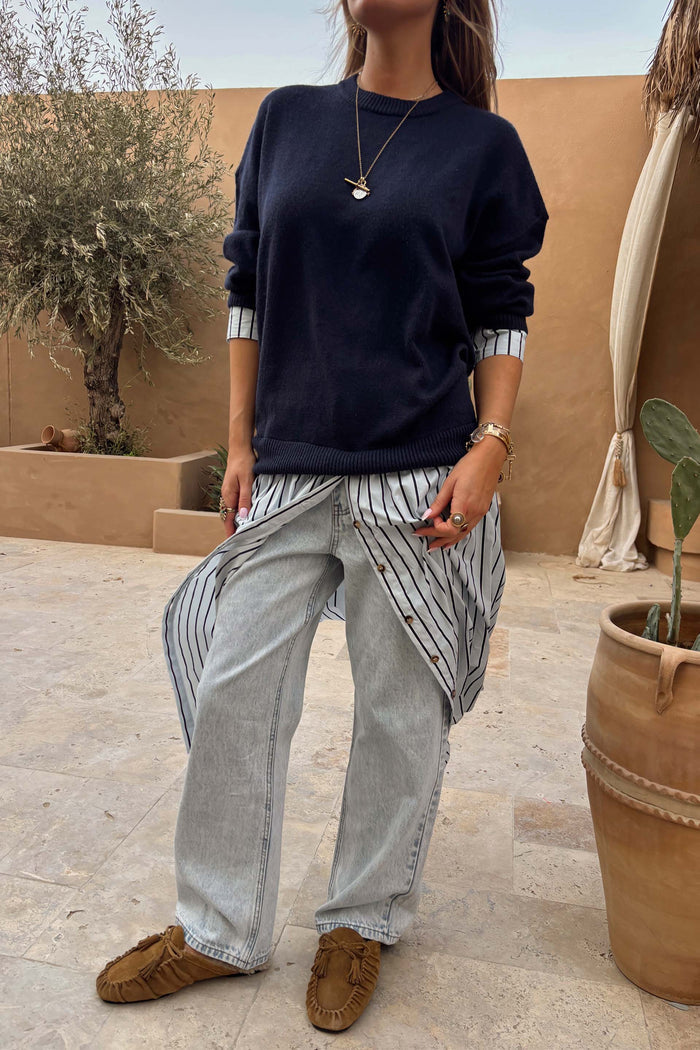 Navy knit dress with a striped cotton skirt, styled as a multi-wear layer over light wash jeans.
