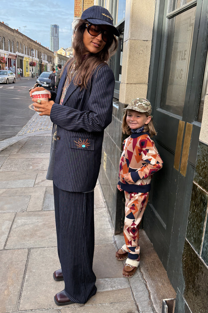 Navy Pinstripe Arden Trousers and matching blazer styled for a smart-casual London look on a city street.