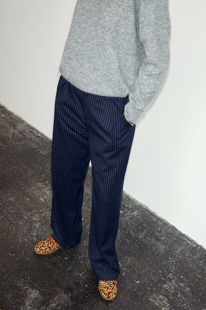 Navy Pinstripe Arden Trousers in a sleek pinstripe print, styled with a grey knit jumper and leopard print shoes.