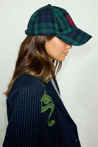 Navy and green tartan cap with red NFD logo embroidery, worn with a pinstripe blazer with snake detail.