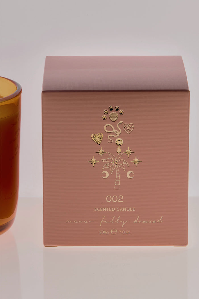 NFD Eau De Parfum Candle 002 packaging in muted pink featuring gold foil palm tree and celestial illustrations.