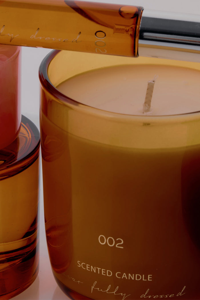NFD Scent 002 amber glass candle with signature branding and notes of pink pepper and creamy vanilla.