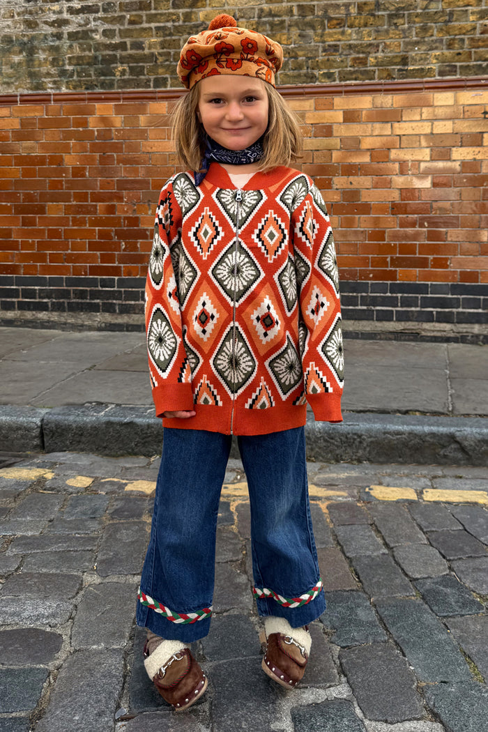 NFD Kids Diamond Bomber in rust orange with a diamond pattern, worn with a floral beret and denim flares.