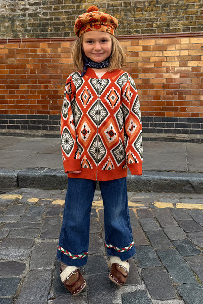 NFD Kids Diamond Bomber in rust orange with a diamond pattern, worn with a floral beret and denim flares.