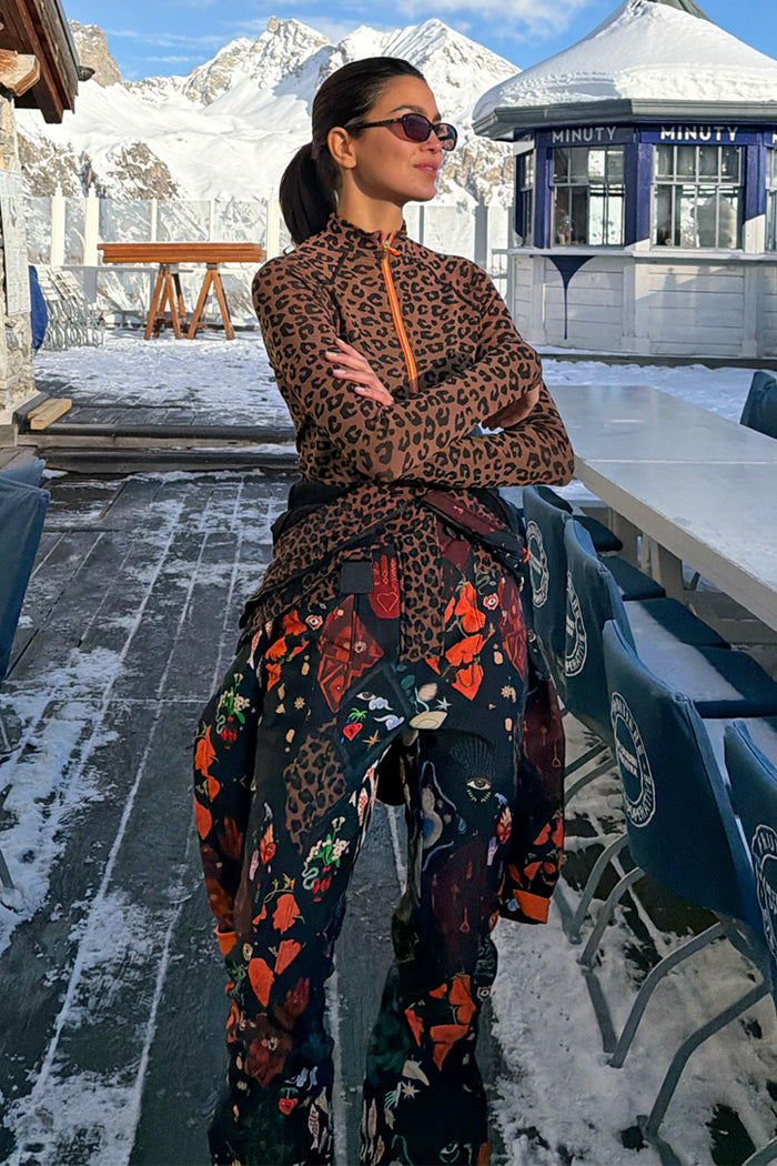 Night Garden Ski Suit featuring iconic leopard and poppy prints, styled at the waist in a snowy mountain landscape.