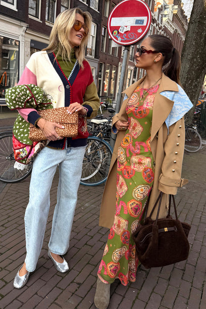 Olive Buckles Mesh Dress featuring western horseshoe motifs, styled under a tan trench coat on a city street.