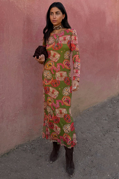 Olive Buckles Mesh Dress with western horseshoe motifs and long sleeves, styled with brown boots and a neck scarf.