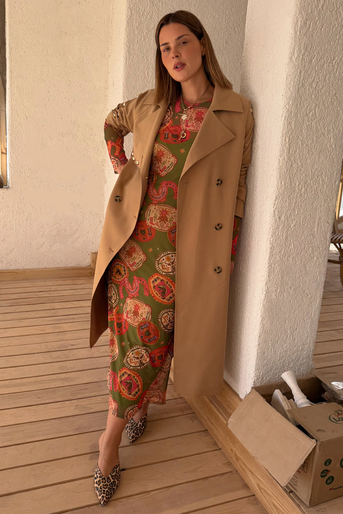 Olive Buckles Mesh Dress with western motifs layered under a tan trench coat, styled with leopard print shoes.