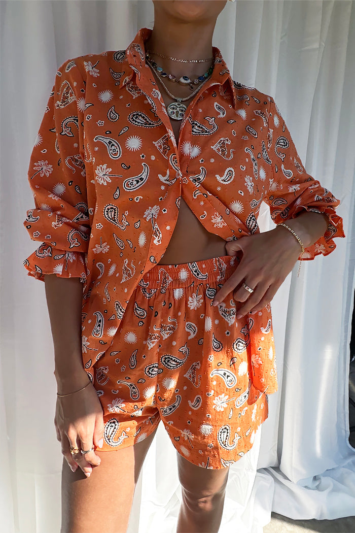 Model wearing the Orange Leopard Elissa Short and matching shirt in a bold paisley and palm print.