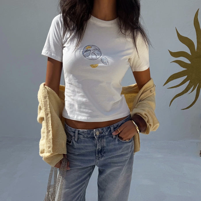 White Oyster Baby T Shirt with lemon print, styled with blue jeans and a yellow cardigan.