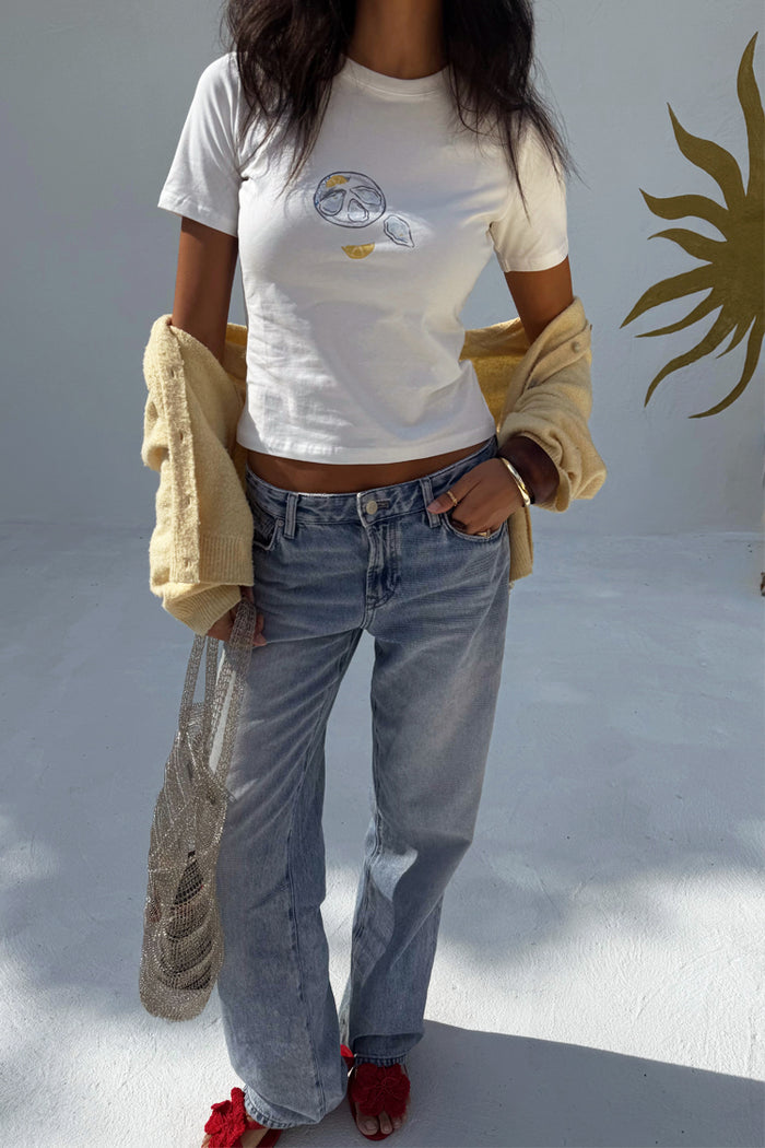 White Oyster Baby T Shirt with a fine line oyster and lemon print, styled with blue jeans and a cardigan.