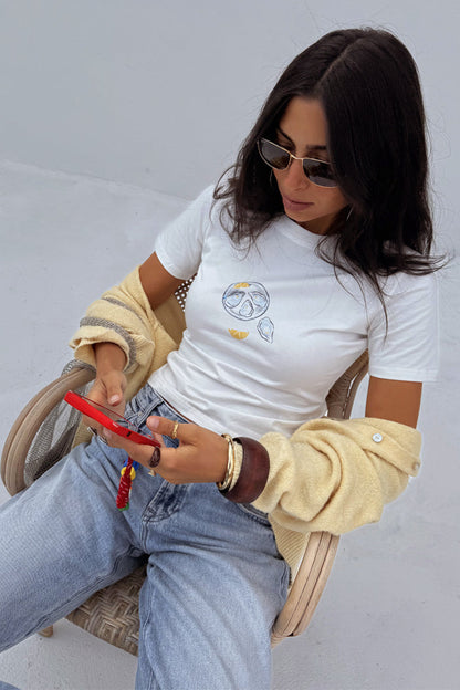 White Oyster Baby T Shirt featuring a fine line oyster and lemon print, styled with denim jeans and a yellow cardigan.