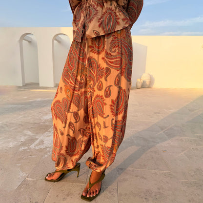 Peach Paisley Balloon Trousers in ECOVERO viscose, styled with khaki heels in a sunny outdoor setting.