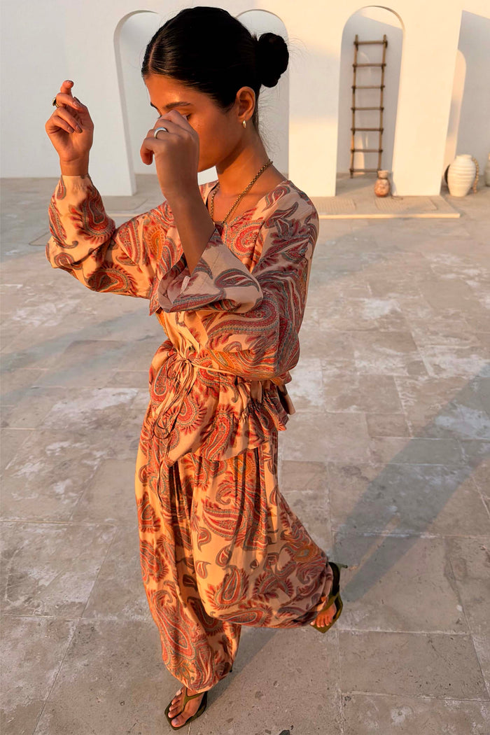 Peach Paisley Balloon Trousers and matching top co-ord in a sun-drenched outdoor setting.