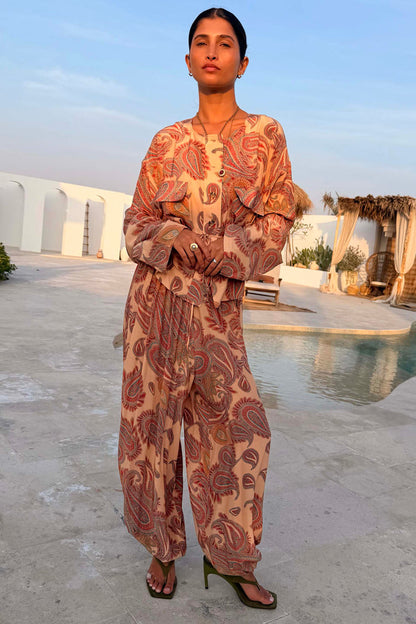 Peach paisley balloon trousers and matching co-ord top on a model in a poolside vacation setting.