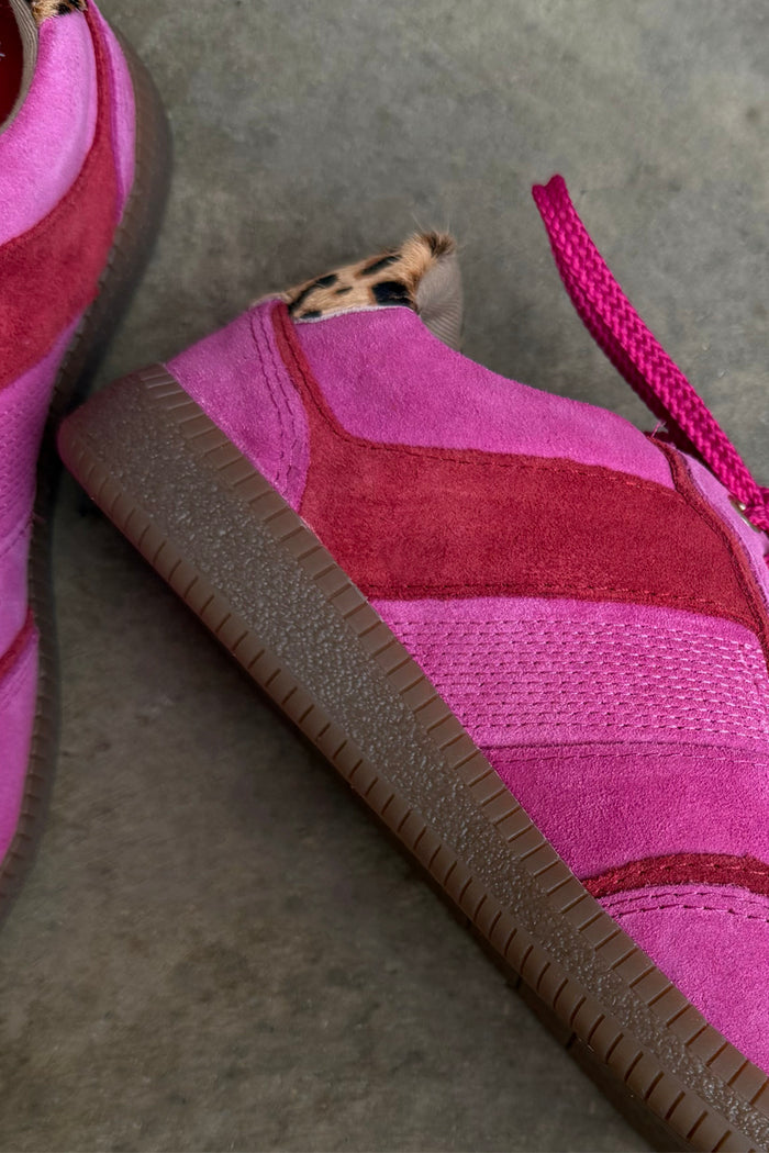 Pink and red leather trainer featuring a leopard print heel and a textured gum sole in a streamlined silhouette.