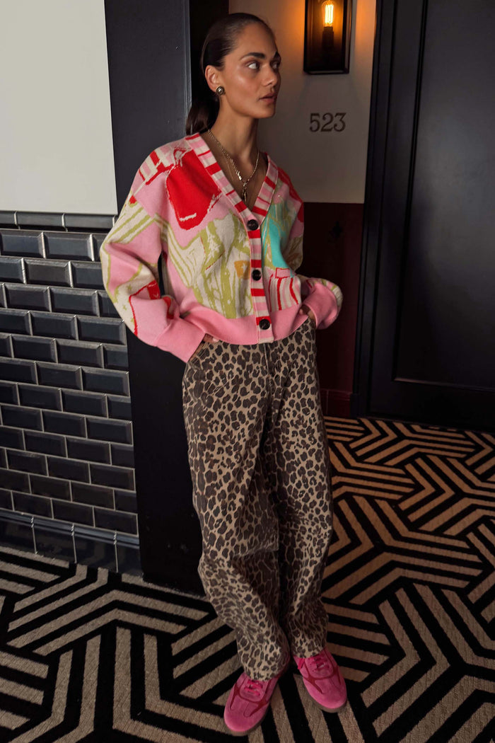 Pink Dallas Cardigan with abstract cowboy motifs and striped trim, styled with leopard print trousers.