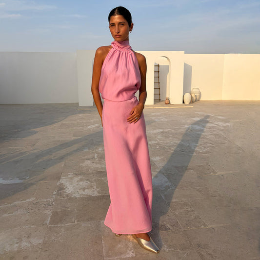 Pink Daphne Skirt in a high-waisted straight fit, paired with a matching halter top and gold shoes in a sunny setting.