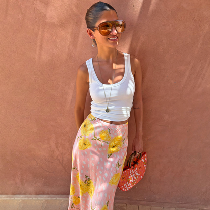 Pink Fawn Poppy Midi Maeva Skirt with yellow poppy print and lace trim, styled with a white tank top and sunglasses.