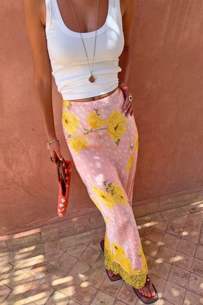 Pink Fawn Poppy Midi Maeva Skirt with yellow floral prints and a contrast lace hem, worn with a white tank top.