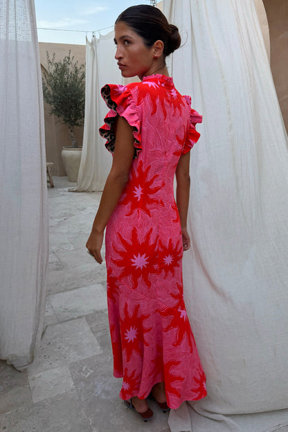 Pink Soleil Remi Dress with red sun motifs, pleated frill sleeves with leopard lining and an asymmetrical skirt.