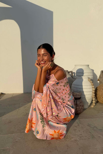 Pink Sun Anais Dress with iconic soleil motifs and gold flecks, shown on a model crouching by white vases.