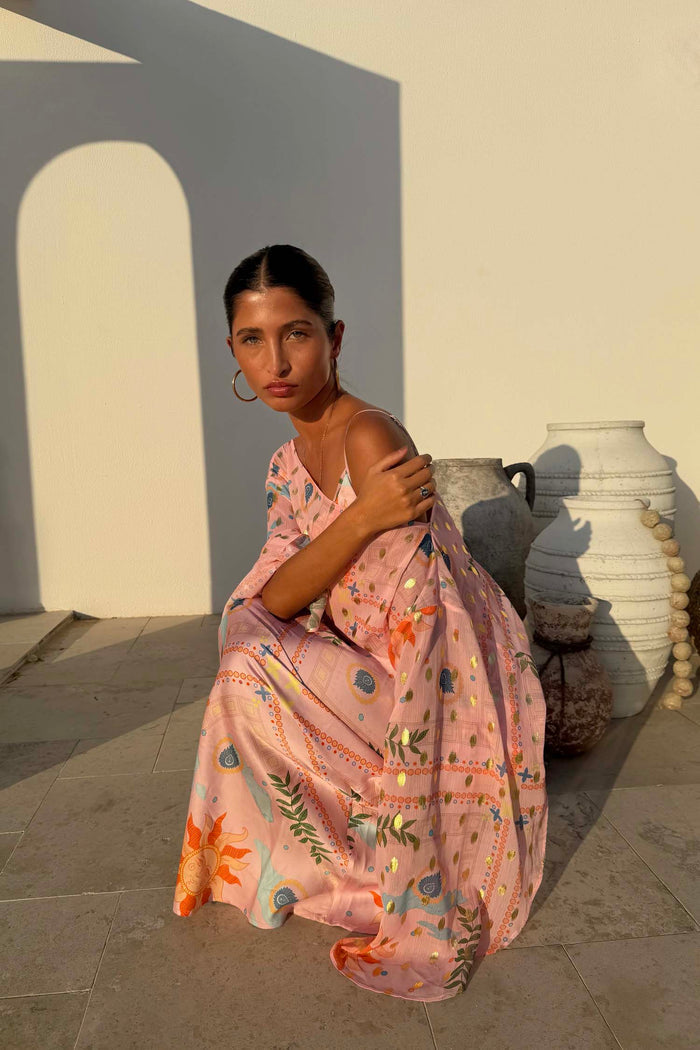 Pink Sun Anais Dress featuring iconic soleil motifs and gold flecks with a sheer off-shoulder top and satin-esque skirt.