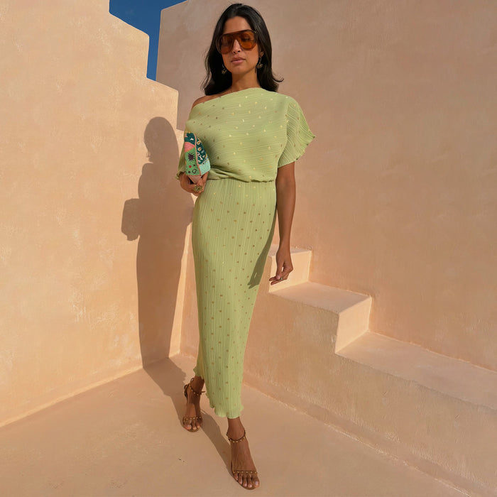 Pistachio Tilly Dress in green plisse with gold flecks and multi-wear off-the-shoulder styling, on a model outdoors.