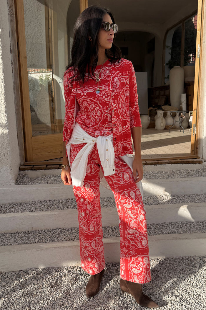 Red bandana print straight leg jeans and cardigan co-ord, styled with a white shirt tied at the waist.