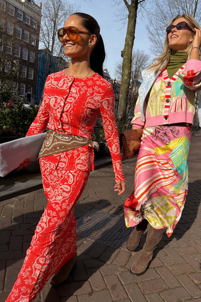 Red Bandana Rib Dorris Skirt styled as a co-ord with a matching cardigan and brown waist tie on a sunny street.