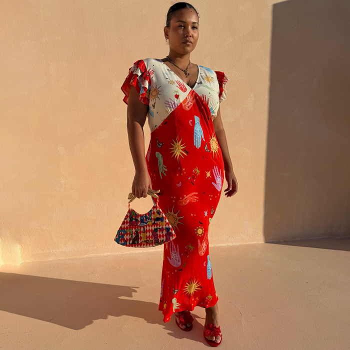 Red Celestial Midi Dress featuring a cream blouson top, red bias-cut skirt and iconic sun and hand prints.