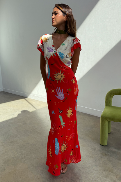 Red and cream Celestial Midi Dress with a sun and hand print, V-neck blouson top and bias-cut skirt on a model.