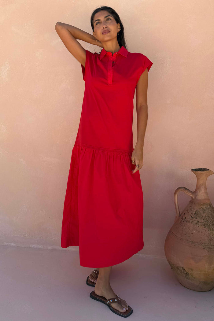 Red Darcy cotton midi dress featuring a collared neckline and dropped waist, designed in London and worn by a model.