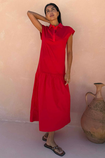 Red Darcy cotton midi dress featuring a collared neckline and dropped waist, designed in London and worn by a model.