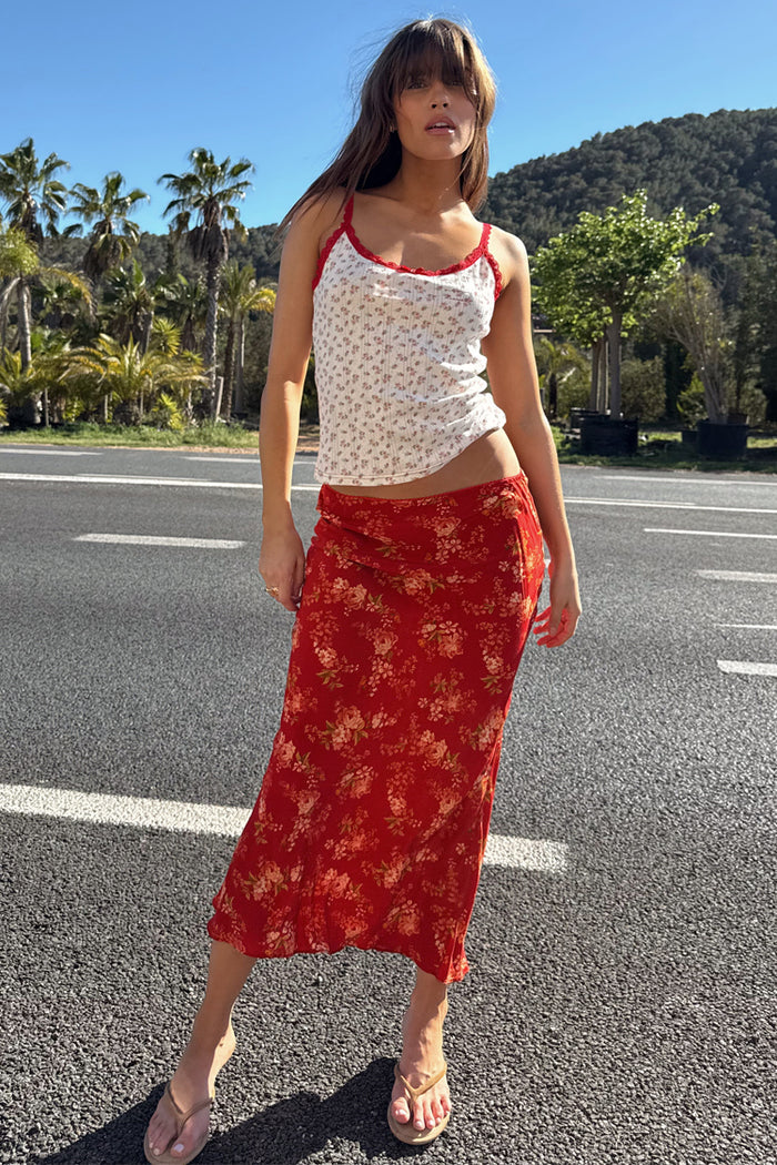 Red Floral Midi Skirt and white pointelle vest with red lace trim, styled for a summer vacation look outdoors.
