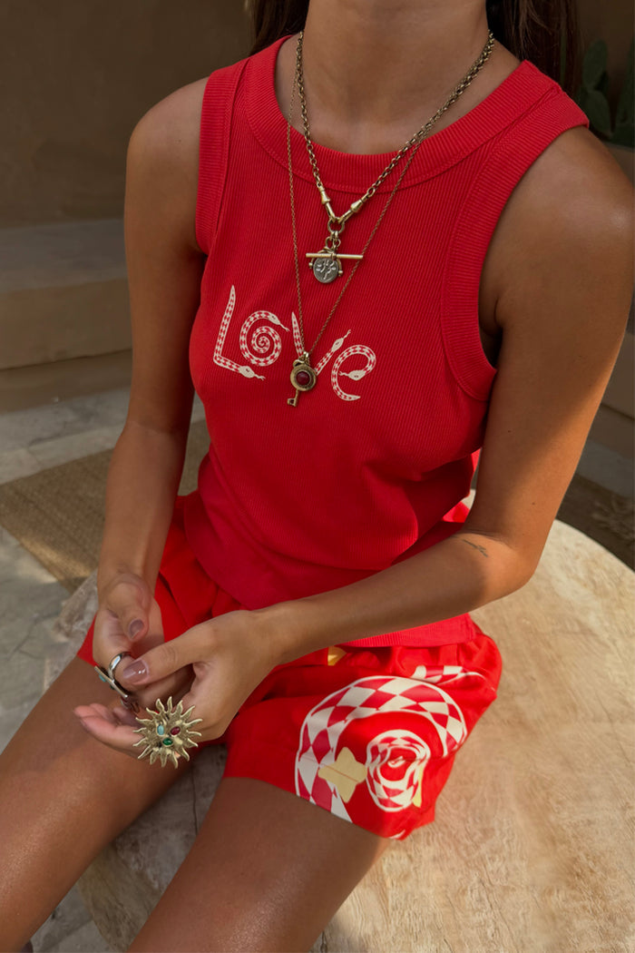 Red Snake Love Rib Tank with white snake motifs on ribbed fabric, styled with gold jewellery and printed shorts.