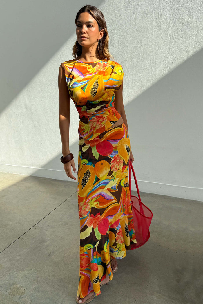 Rio A-Symmetric Skirt in a multi-coloured fruit print, styled with a matching co-ord top and red bag.