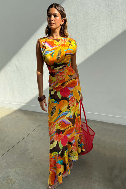 Rio A-Symmetric Skirt in a multi-coloured fruit print, styled with a matching co-ord top and red bag.