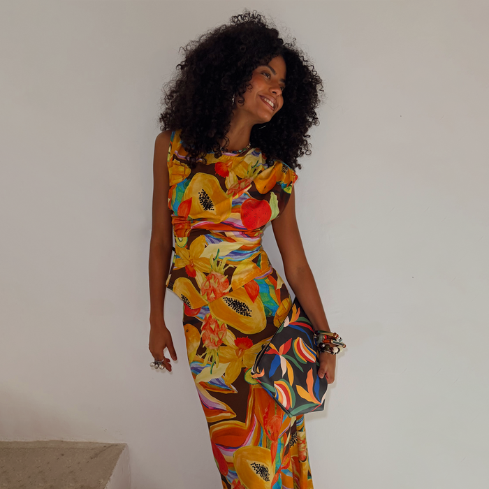 Rio A-Symmetric Top in a multicoloured fruit print, styled as a co-ord set with a matching skirt and clutch bag.