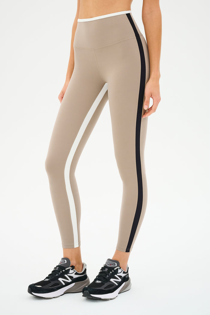 Someone is sporting the SPLITS59 Sam High Waist Rigor 7/8 leggings in Latte/Black, along with black New Balance sneakers.