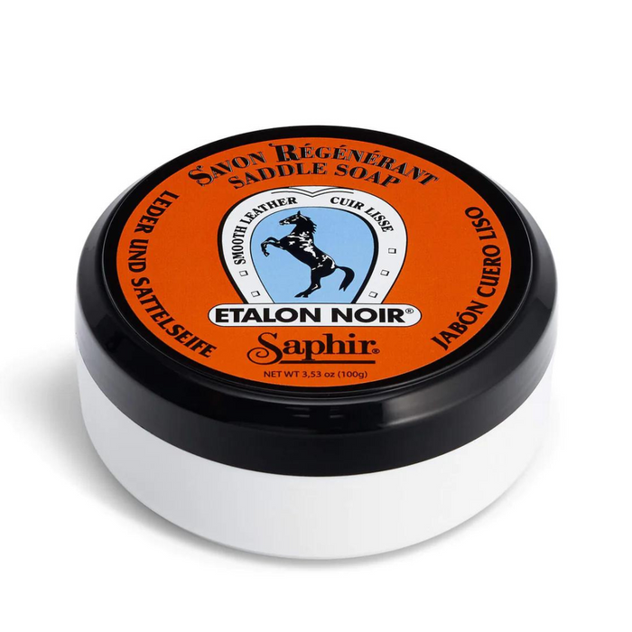 A jar of Saphir Etalon Noir saddle soap with a black lid and orange label, indicating it is a leather cleaning product.