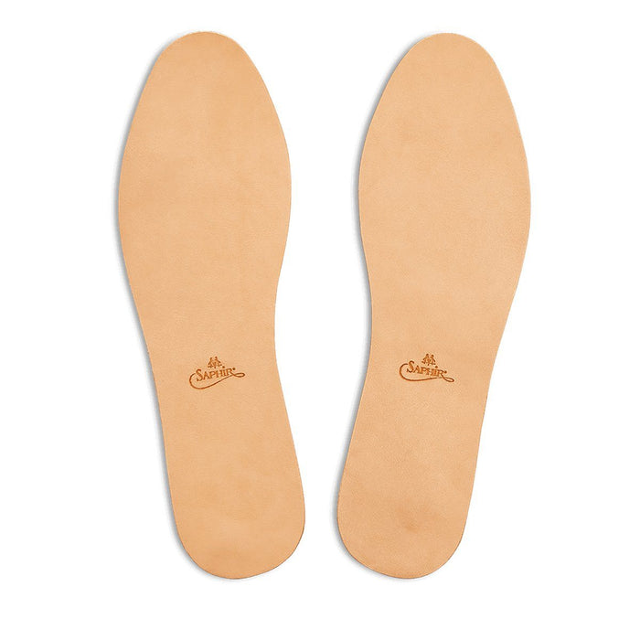 A pair of beige Saphir Medaille D'Or leather insoles with the brand's logo embossed at the heel.