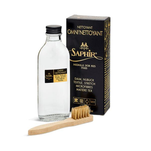 A bottle of Saphir Medaille D'Or Omni-Nettoyant Suede Multicleaner with a small suede brush included in front of its packaging box.