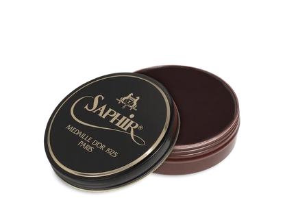 A round tin container of Saphir Medaille D'Or shoe wax polish with black lid and gold lettering.