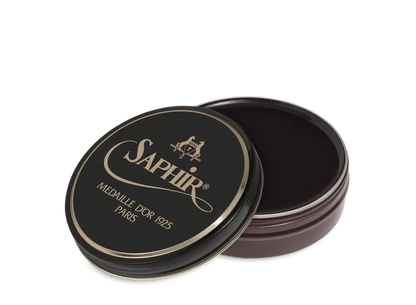 A round tin container of Saphir Medaille D'Or shoe wax polish with black lid and gold lettering.